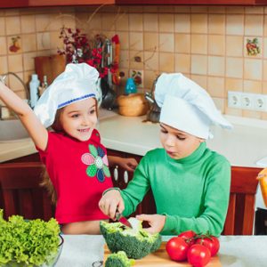 happy family funny kids are preparing the a fresh vegetable salad in the kitchen Cocina en familia